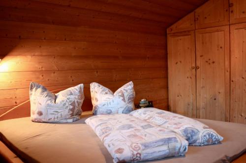 Una cama en una cabaña de madera con almohadas. en Eggerhof, en Neustift im Stubaital