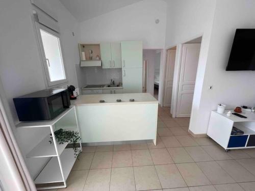 Il comprend une cuisine avec un comptoir et une télévision. dans l'établissement Villa Caroline - Maison dans belle résidence avec piscine - Sainte Lucie de Porto Vecchio, à Sainte-Lucie de Porto-Vecchio