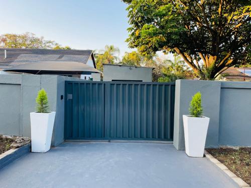 a gate with two potted plants in front of a fence at Tranquil Unit in Phalaborwa