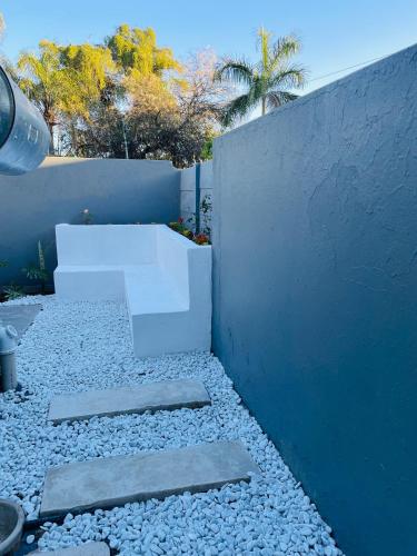 a white bench sitting on rocks next to a wall at Tranquil Unit in Phalaborwa