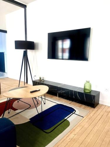 Il comprend un salon doté d'une table et d'une télévision à écran plat. dans l'établissement Nouveau - Le petit Auguste - 2ch - Port de plaisance, au Havre