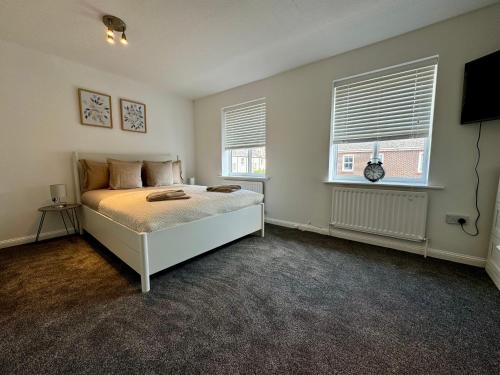 a bedroom with a bed and two windows at John Street Stays in Southampton