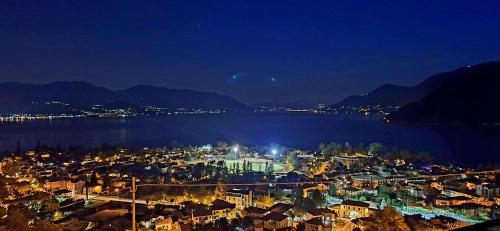 a night view of a city and the water at Sole & Lago-Lake in Maccagno con Pino e Veddasca