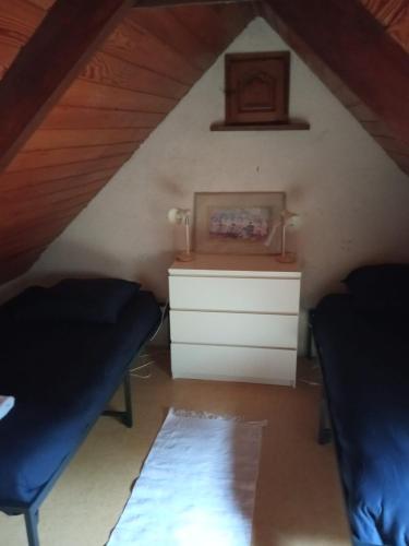 a room with two beds and a dresser in a attic at Camping Vieilles Charrues Petit-déjeuner navette et priscine inclus dans le prix proche Carhaix in Motreff