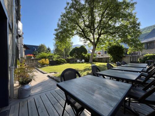 a row of wooden tables and chairs on a deck at La Sainthilarienne in Saint-Lary-Soulan