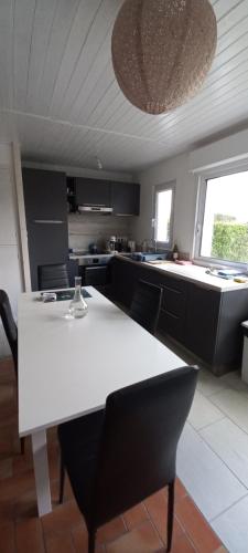 une cuisine avec une table blanche et des chaises noires dans l'établissement Le cocon du port Appartentre port et plages, à LʼHerbaudière