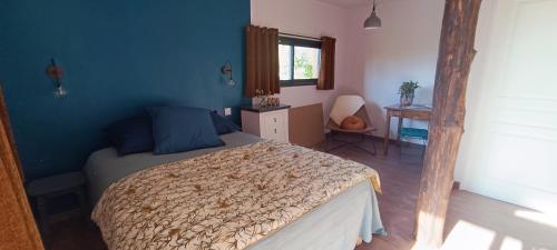 une chambre avec un lit et un mur bleu dans l'établissement La chouette, à La Malonie