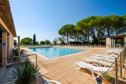 - une piscine avec des chaises longues blanches et des arbres dans l'établissement Appartement Vaugrenier Presidences, à Villeneuve-Loubet