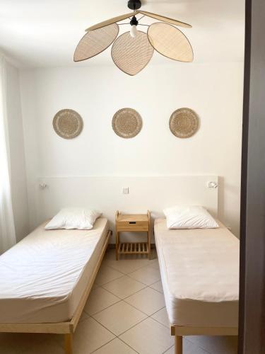 Cette chambre dispose de 2 lits et d'un ventilateur de plafond. dans l'établissement Lozarifamily, à Belgodère
