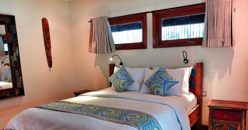 a bedroom with a bed with blue and white pillows at Scallywags Beach Club in Gili Air