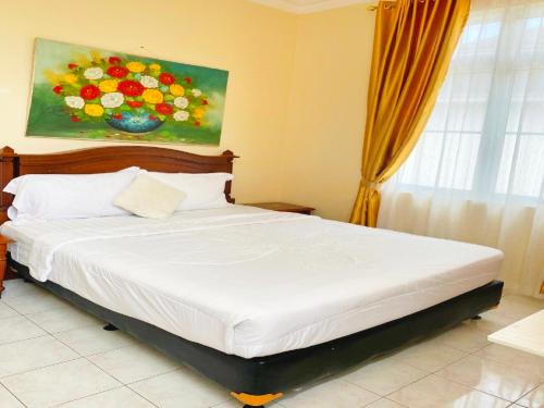 Villa Luxury kota bunga في Cikundul: غرفة نوم بسرير مع لوحة بالورود