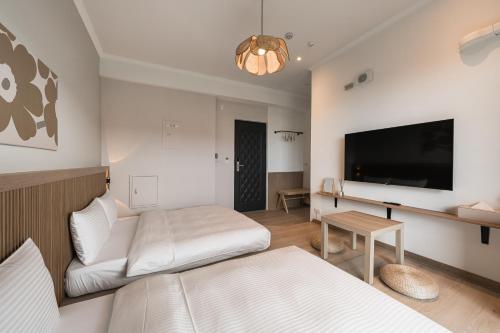 a living room with two beds and a flat screen tv at Chunns Inn in Hengchun
