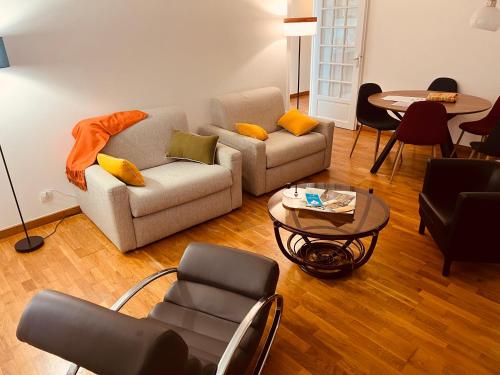 a living room with two couches and a table at Appartement standing avec jardin, 4 personnes, stratégiquement situé in Mantes-la-Jolie