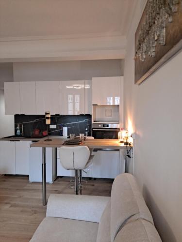 une cuisine avec des armoires blanches, une table et un canapé dans l'établissement loft notre dame annecy, à Annecy