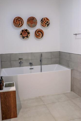 a bath tub in a bathroom with three plates on the wall at Cresta Mowana Safari Resort & Spa in Kasane