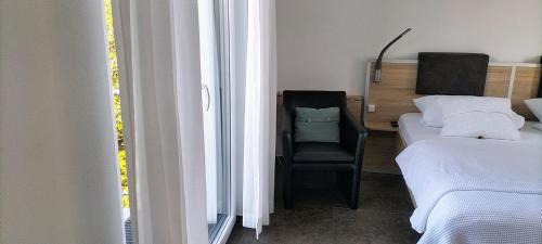 a bedroom with a bed and a chair next to a window at Alte Stadtmauer - Apartment in Sinsheim
