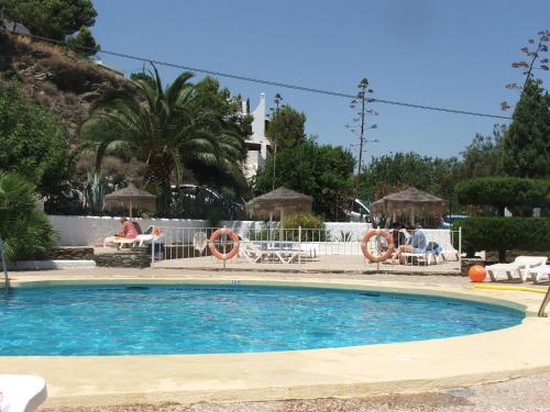 a swimming pool in a resort with people sitting on chairs at La Parata Apartments in Mojácar