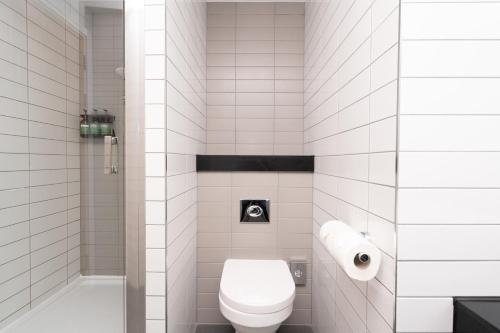 a white tiled bathroom with a toilet and a shower at Crowne Plaza Newcastle - Stephenson Quarter by IHG in Newcastle upon Tyne