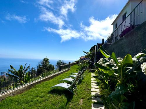 a row of benches sitting on a hill near the ocean at Meerblick - 3-Bett Villa mit Terrassen & Hot-Tub in Fajã da Ovelha