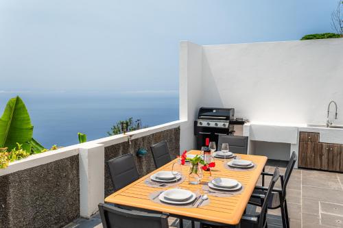 a table and chairs on a balcony with a kitchen at Meerblick - 3-Bett Villa mit Terrassen & Hot-Tub in Fajã da Ovelha