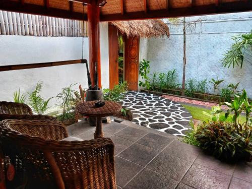 an outdoor patio with wicker chairs and an umbrella at Scallywags Beach Club in Gili Air