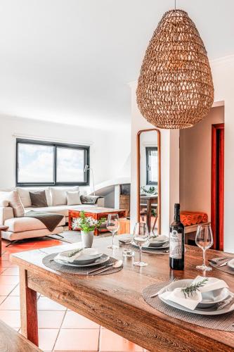 a living room with a table with plates and wine glasses at Meerblick - 3-Bett Villa mit Terrassen & Hot-Tub in Fajã da Ovelha