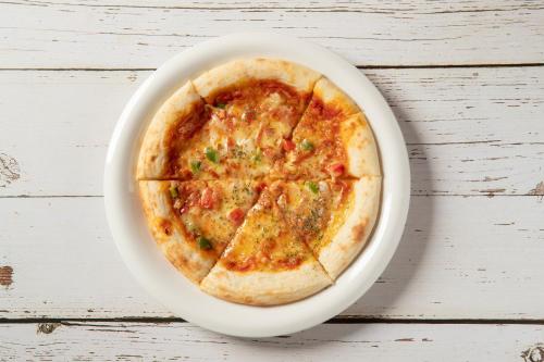 a pizza on a white plate on a table at ホテル ブルジュア 久留米 Hotel Bvljua -レジャーホテル- in Kurume
