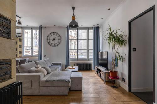 a living room with a couch and a clock on the wall at Appartement spacieux au cœur d'Angers étage 1 - 6 personnes in Angers