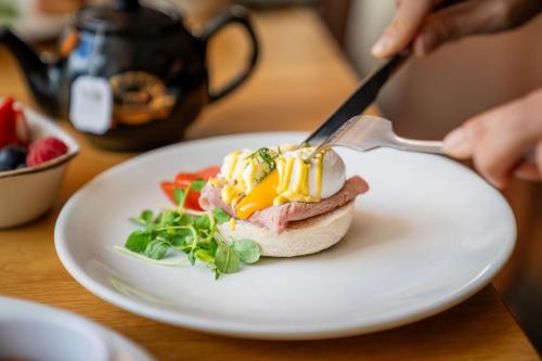 a person cutting into a sandwich on a plate with a knife and fork at Crowne Plaza Newcastle - Stephenson Quarter by IHG in Newcastle upon Tyne