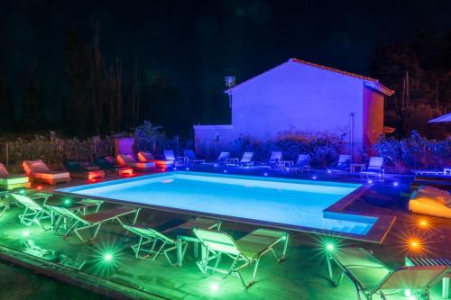 a swimming pool at night with chairs and lights at BSP RENT ROOMs in Paralia Sikias