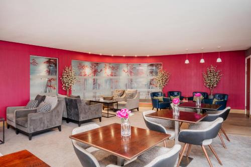 a living room with red walls and tables and chairs at Crowne Plaza Newcastle - Stephenson Quarter by IHG in Newcastle upon Tyne