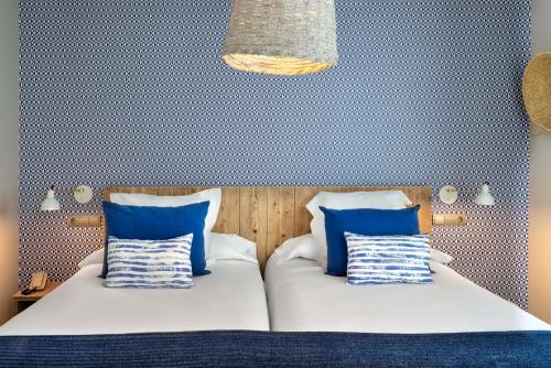 a bedroom with two beds with blue and white pillows at Vincci Puertochico in Santander