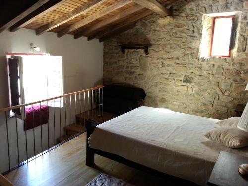 a bedroom with a bed and a stone wall at Charming House Óbidos in Óbidos