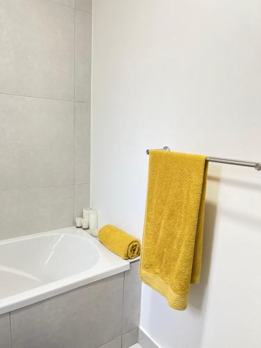 a bathroom with a white tub and a yellow towel at ventura 250 in Sandton