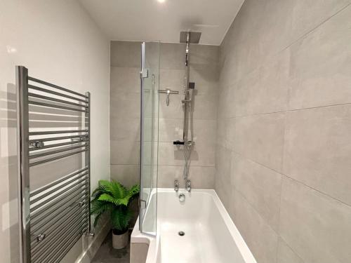 a bathroom with a shower and a bath tub at The Cadogan Suite by Harrods in London