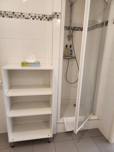 La salle de bains est pourvue d'une douche et d'étagères blanches. dans l'établissement 2 Pièces calme proche Paris, à Suresnes