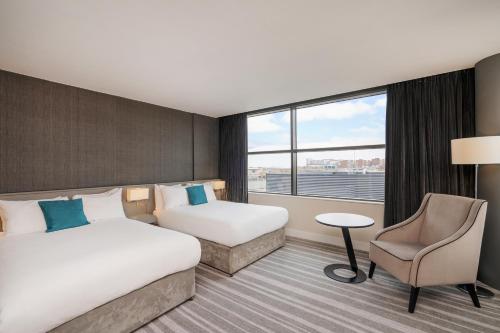 a hotel room with two beds and a chair at Crowne Plaza Newcastle - Stephenson Quarter by IHG in Newcastle upon Tyne