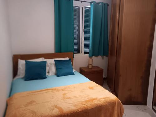 a bedroom with a bed with blue pillows and a window at Jose's cozy little home in Funchal