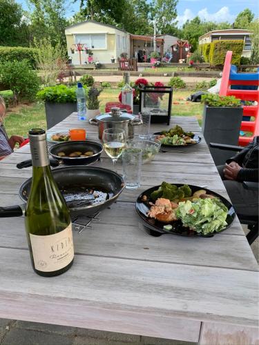 un tavolo con una bottiglia di vino e un piatto di cibo di Verzorgd chalet in de Betuwe op park met natuurbad a Beesd
