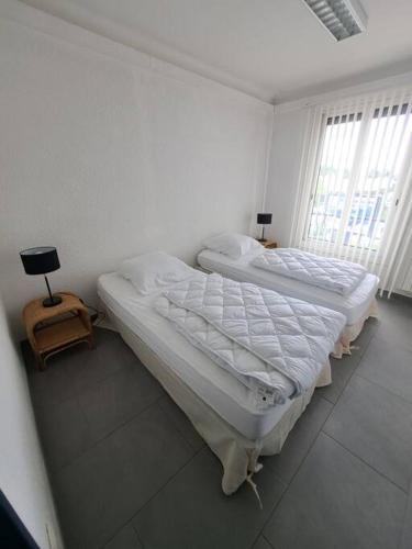 deux lits dans une chambre blanche avec une fenêtre dans l'établissement Joli T3 3 min gare Perpignan, à Perpignan