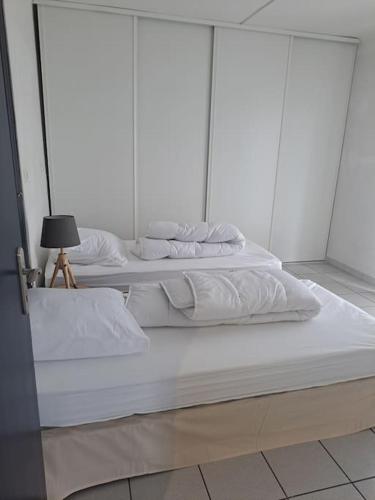 3 lits blancs dans une chambre avec une lampe dans l'établissement Joli T3 3 min gare Perpignan, à Perpignan