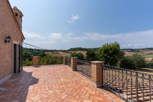 a brick patio with a iron fence and a view at Villa Dolce Vita - Vista Colline, Jacuzzi, 3Suites & 5min dal mare in Lapedona