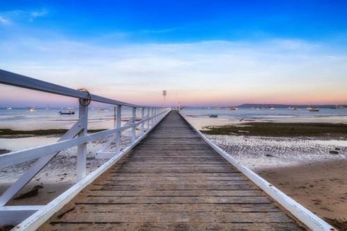 a wooden boardwalk leading to the beach at sunset at Blairgowrie Beach Townhouse Opposite the beach! in Blairgowrie
