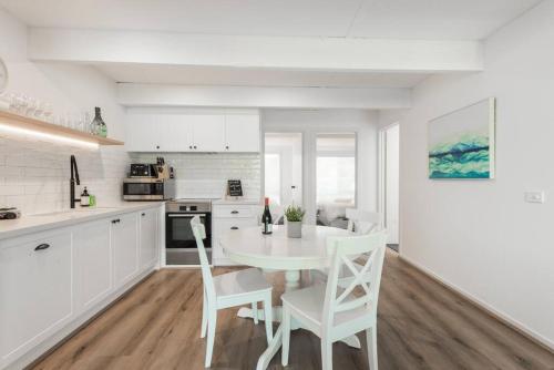 a white kitchen with a white table and chairs at Blairgowrie Beach Townhouse Opposite the beach! in Blairgowrie