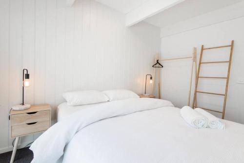 two white beds in a white bedroom with a night stand at Blairgowrie Beach Townhouse Opposite the beach! in Blairgowrie