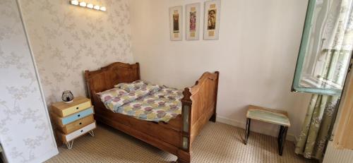 a small bedroom with a wooden bed and a dresser at L'ancienne Forge - a stylish medieval holiday home in Confolens
