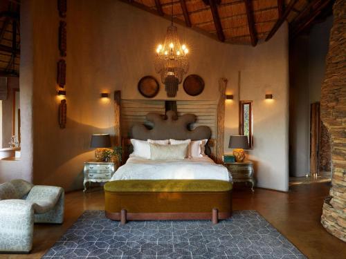 a bedroom with a large bed and a chandelier at Molori Safari in Derdepoort