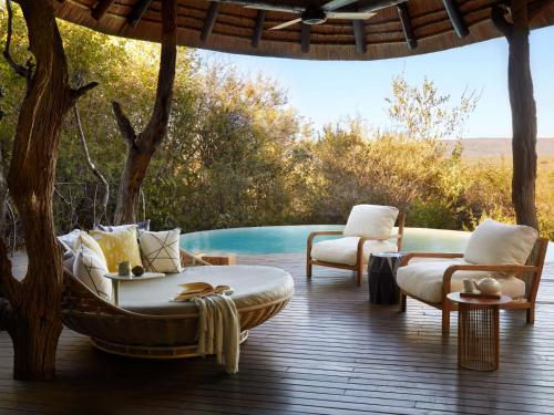 a patio with two chairs and a table and a pool at Molori Safari in Derdepoort