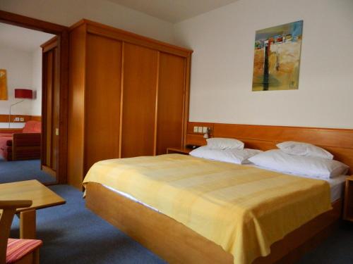 a bedroom with a bed with a wooden headboard at Hotel Kalma, Kalma Villa, Apart Hotel in Hévíz