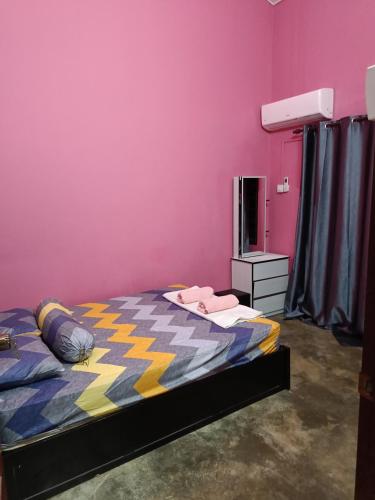 a bedroom with a bed and a pink wall at Lin's Homestay in Port Dickson